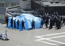 Poliziotti e funzionari della sicurezza intorno ad un telone che copre un drone radioattivo sul tetto della residenza ufficiale del Primo Ministro Shinzo Abe a Tokyo il 22 aprile 2015.